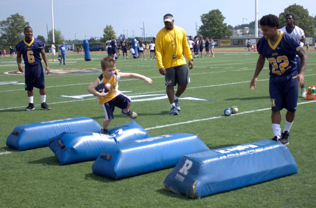 Above, defensive line coach Freddie Roach observes a training drill. Top right, Freshman Dayshaun Matlock runs a drill with a young Racer fan.
Bottom right, Junior Duane Brady and Roach offer advice as a young player completes an exercise. ||Kirstin Allen//The News