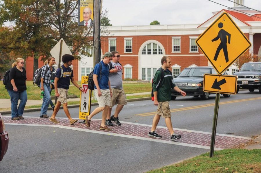 Kate Russell/The News
Students cross 16th Street on one of the crosswalks with a safety sign in the middle of it. This sign was replaced after being hit by several vehicles.