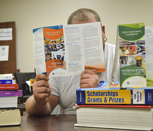 Photo Illustration by Hannah Fowl/The News
A student reads brochures on how to take out loans, the different loans available, receiving scholarships and grants and how to pay for college.
