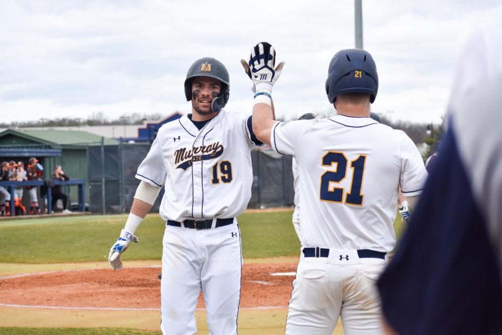 Junior outfielder Jake Slunder high-fives junior outfielder Skylar McPhee. (Photo by Paige Bold/The News)