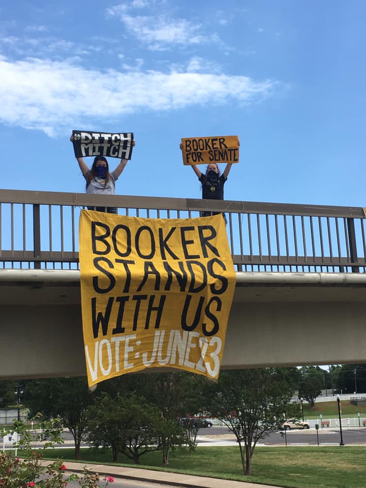 Ashlen Grubbs, junior from LaRue County, and Jordyn Krueger, junior from LaRue County, participate in a banner drop on June 13 in support of senate candidate Charles Booker. (Photo courtesy of Sunrise Movement Murray)