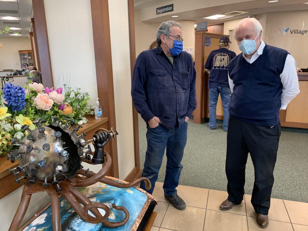 George Bandarra, owner of Bandis Iron Hammer, created a sculpture of the virus that causes COVID-19. Bandarra, pictured left, talks about the sculpture with Chief Medical Officer Bob Hughes, to the right.