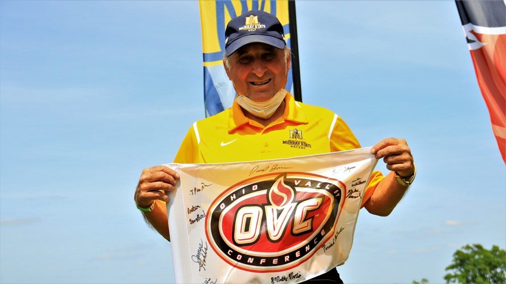 Head Coach Eddie Hunt poses with his OVC pin flag, which the other coaches in the conference signed to celebrate his 20-year career at Murray State. (Photo courtesy of Racer Athletics)