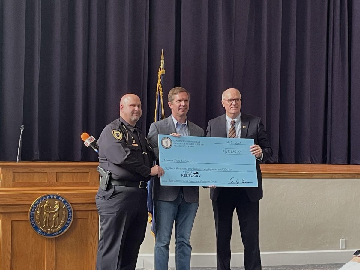 Gov. Andy Beshear (center) presents interim police chief Ryan Orr (left) with a check to benefit the University Police Department. (Jill Smith/The News) 