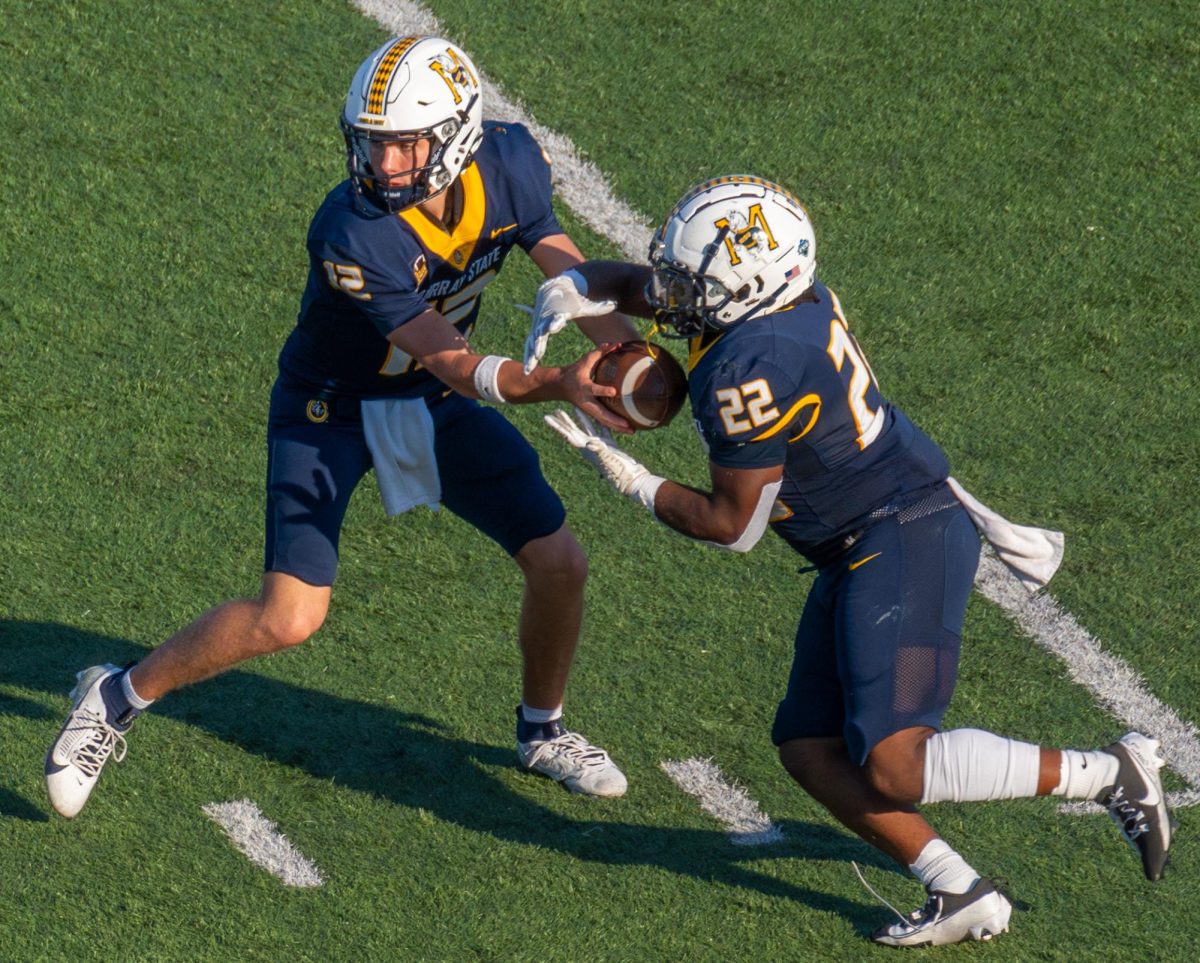 Sophomore quarterback Jameson Holcomb hands the ball off to Freshman running back Kevin Emmanuel. 