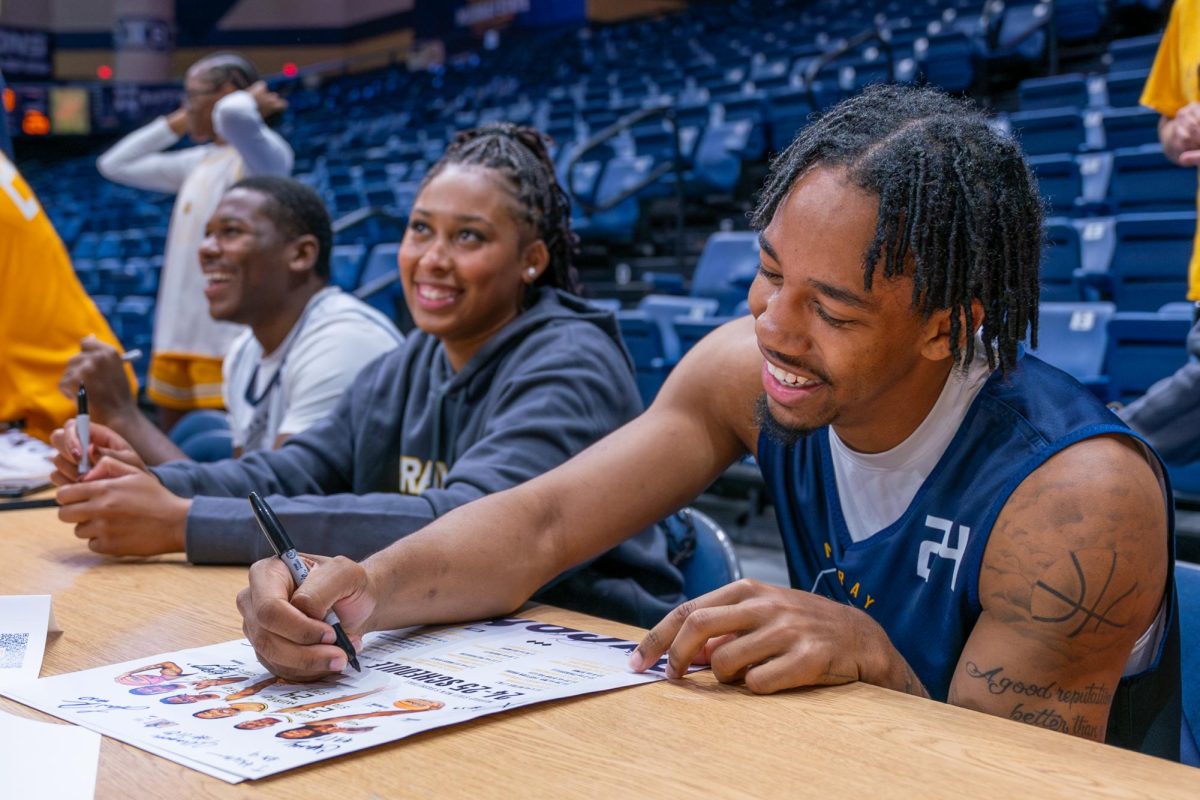 Senior guard JaCobi Wood smiles while signing autographs with Destiny Thomas and Nick Ellington. 