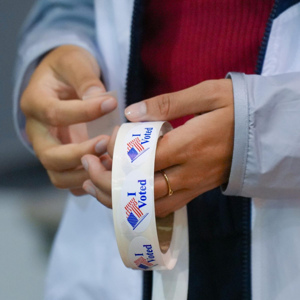 A volunteer hands out stickers to voters after casting their ballots. 