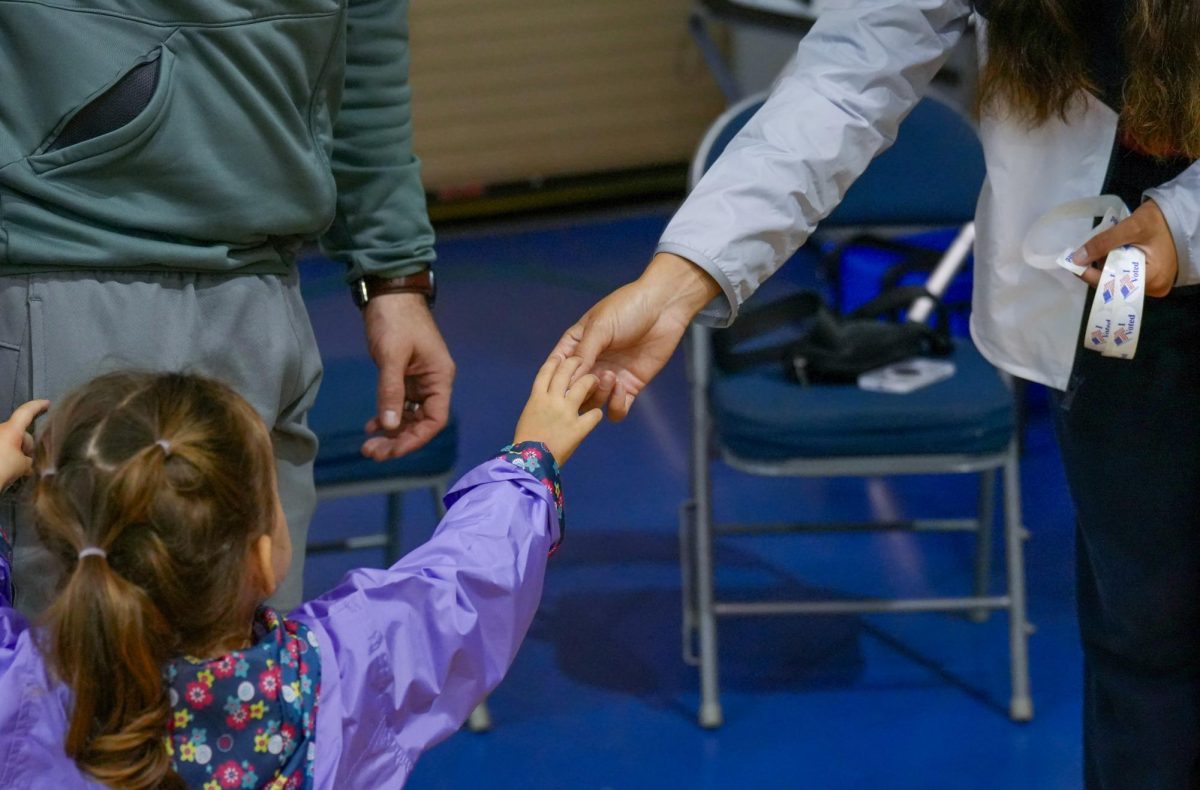 A volunteer hands a sticker to a child. 