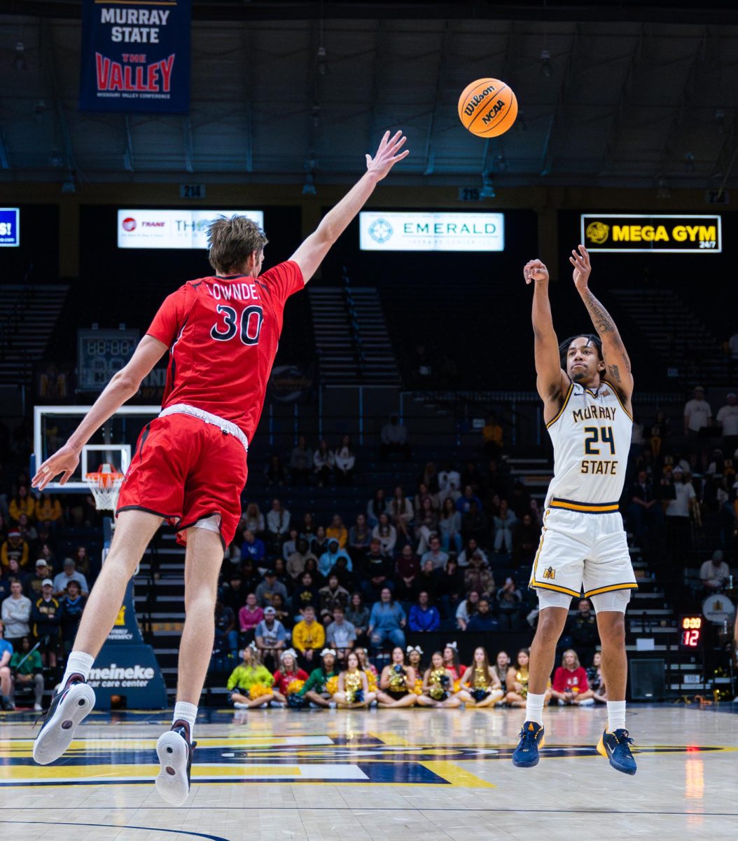 Senior guard JaCobi Wood shoots a three over an outstretched defender.