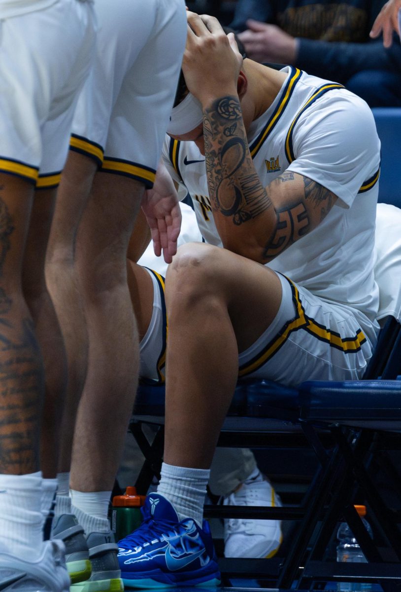 Junior forward KyeRon Lindsay holding his head on the bench.