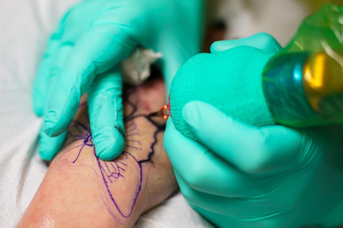 Tattoo artist Ryun King inks a butterfly onto a customer's wrist. 