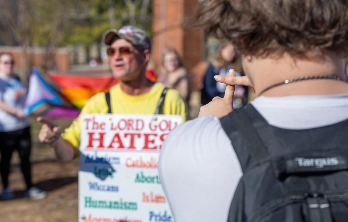 A student holds up the sign of the cross in the face of Bourgault.