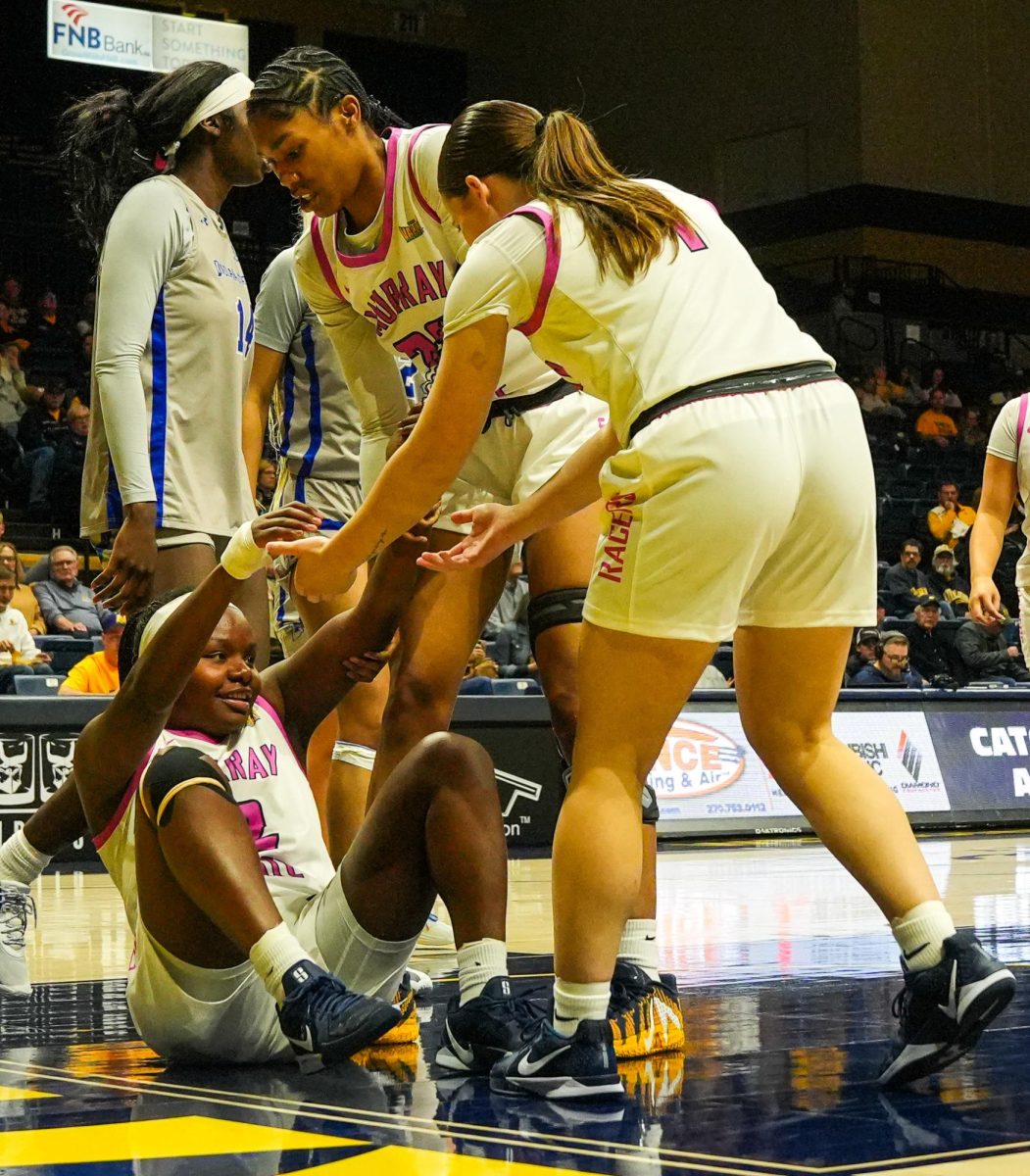 Junior Forward Sharnecce Currie-Jelks and Junior Guard Hallie Poock help Junior Guard Haven Ford off the ground after a play. 