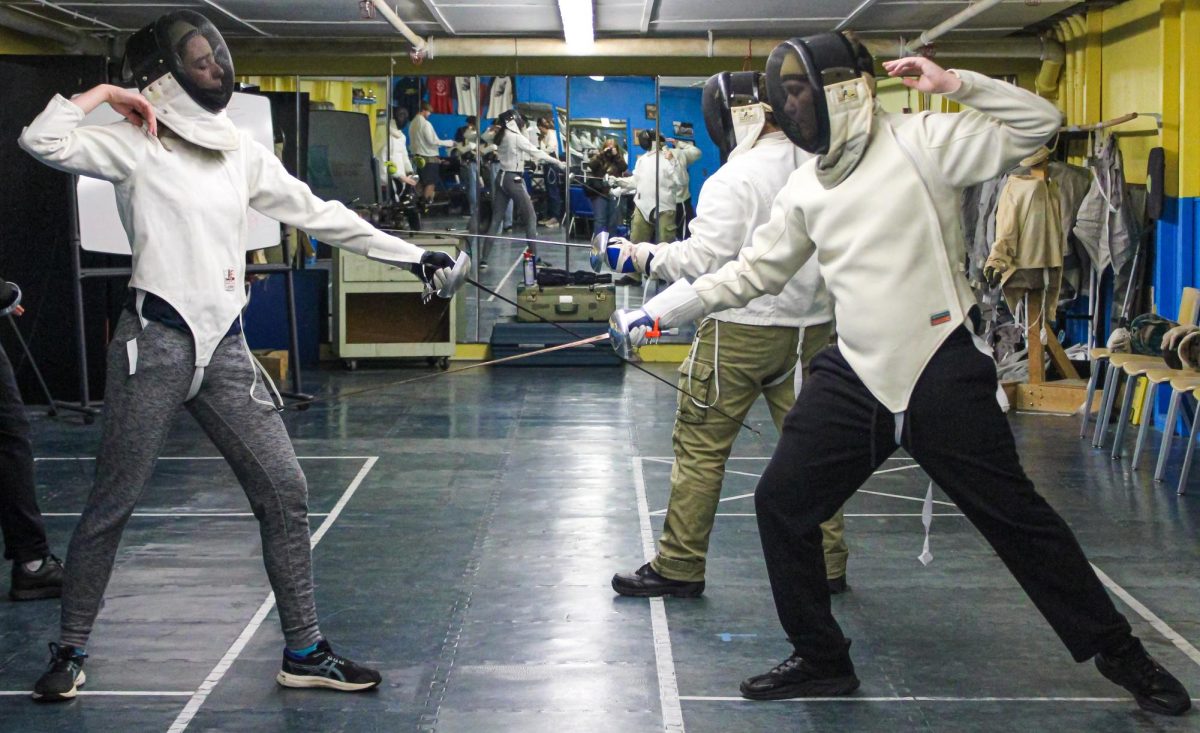 Junior McKenna Ice and freshman Harper Horton begin their duel in the fencing club's practice room.